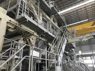 Escaleras y pasarelas metálicas de máquina industrial bajo puente grúa amarillo
