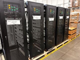 Racks negros con puertas perforadas e indicadores sobre palés en nave