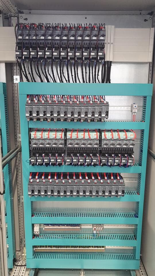Interior de panel con estructura turquesa y filas de disyuntores con cableado identificado