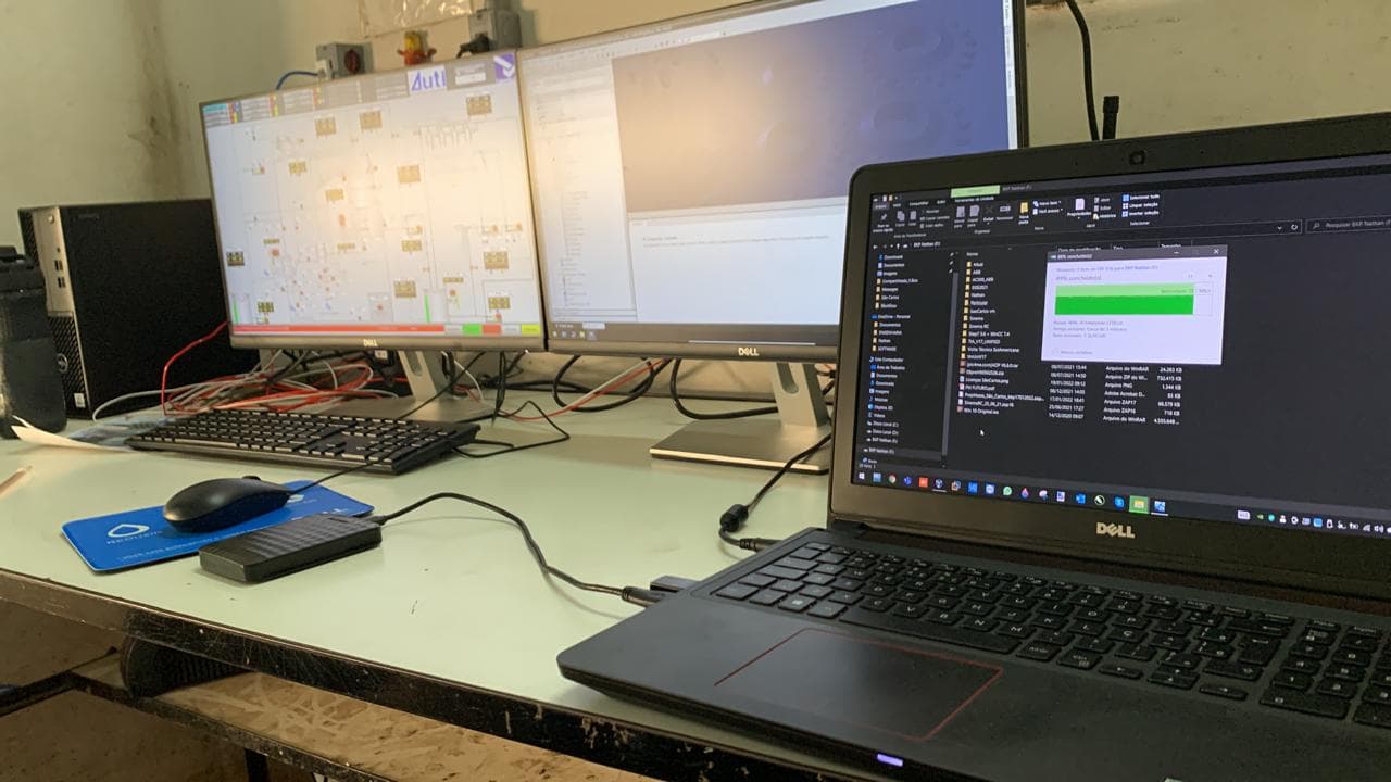 Mesa con dos monitores de pantalla de proceso y portátil copiando archivos
