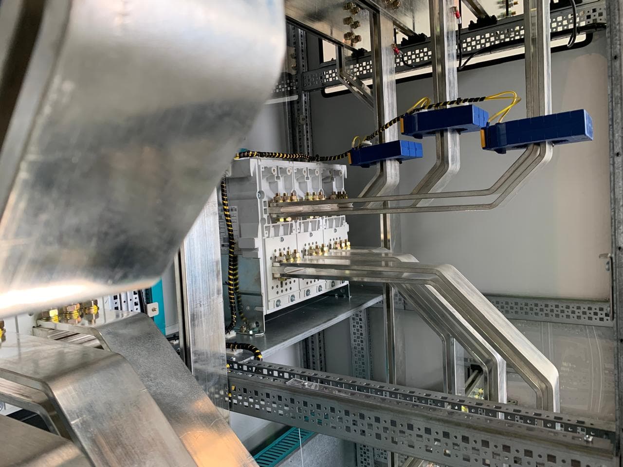 Detalle de barras dobladas y sensores azules dentro de un panel de potencia